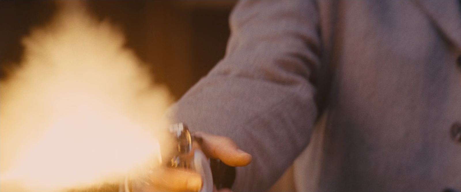 A revolver firing at close range, a large soft plume of muzzle smoke filling the left of the frame.