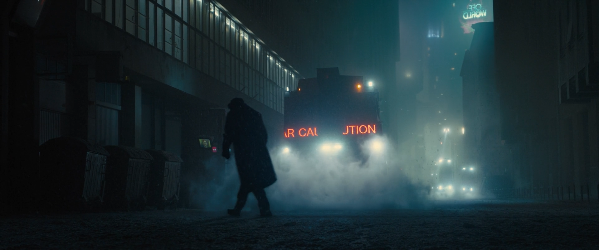 Shot 0160 from Blade Runner 2049 at 01:15:14:12. An illuminated red sign on the vehicle is the only warm element in a blue-black street; steam catches the light from behind and separates the walking figure from the buildings.