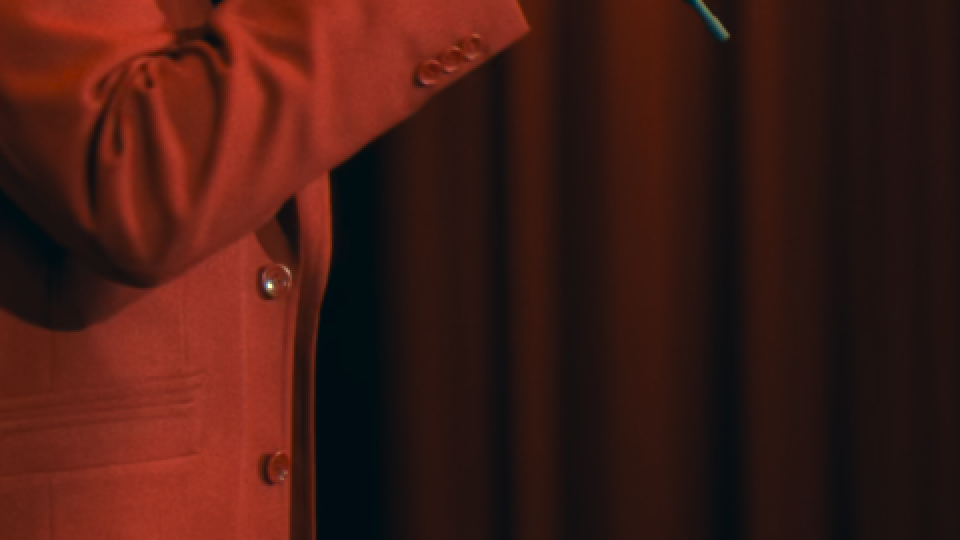 A red coat against a red stage curtain in low light.