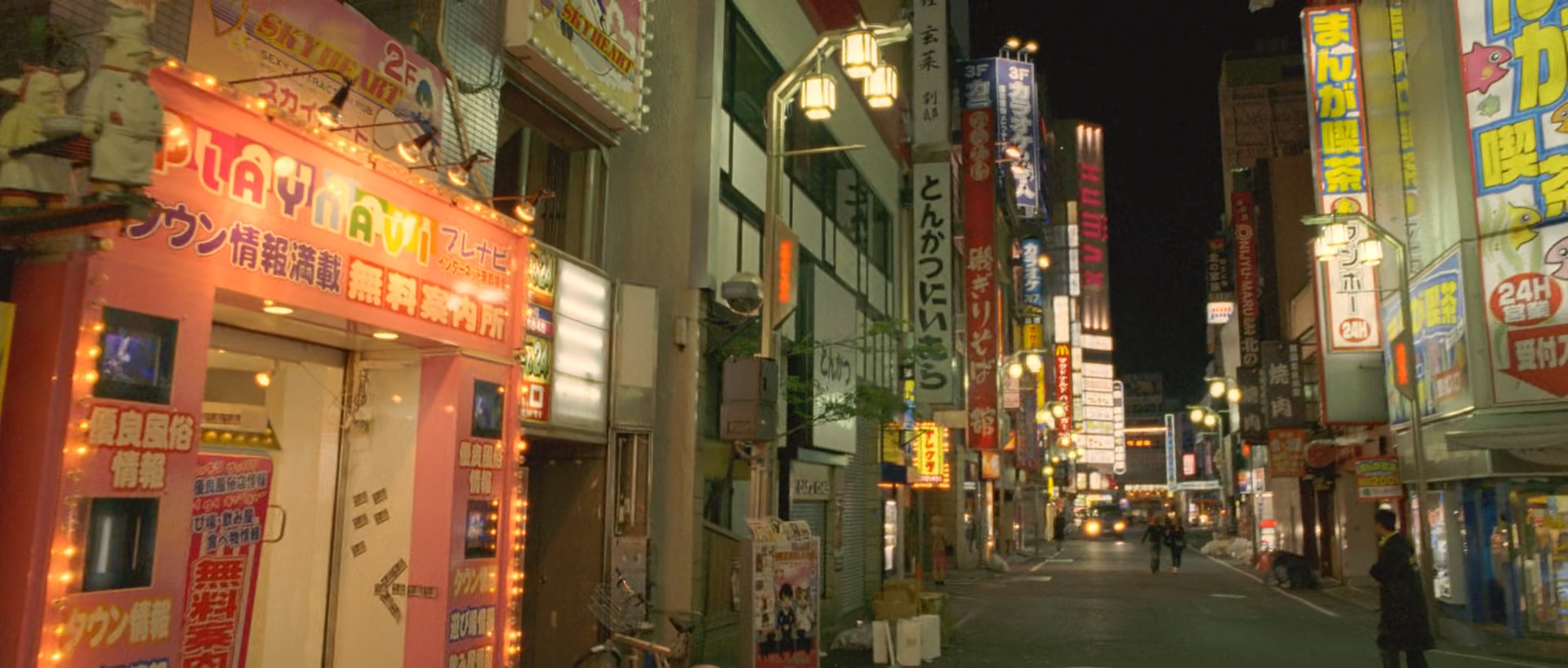 A narrow Tokyo street at night lined with illuminated vertical signs and storefronts, with small figures and cars receding toward the centre.