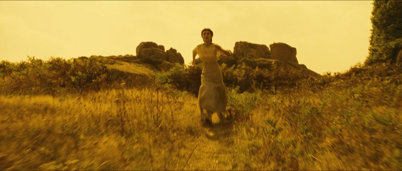 A woman running through a luminous yellow field beneath a pale sky.
