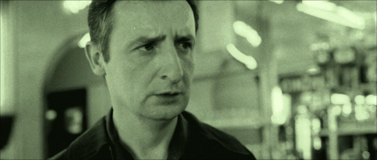A man in a desaturated green-grey transit interior.